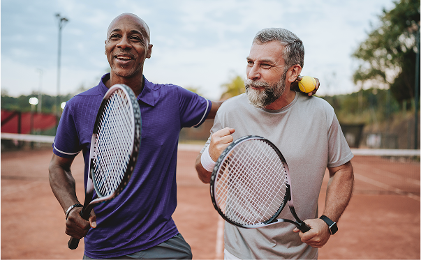 Two men holding tennis rackets celebrate their win on the court.