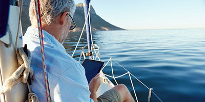 Senior man on sailboat using a tablet