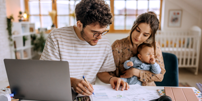 Young couple doing financials while holding their baby