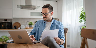 Man on a computer reviewing his financials in the kitchen