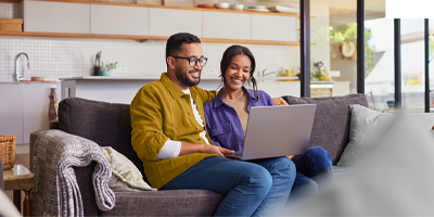 Couple sitting in their living room with a laptop reviewing life insurance basics
