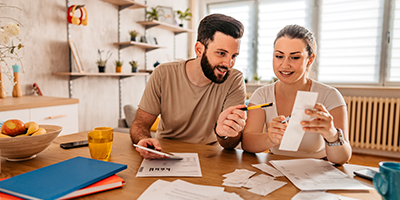 A young couple, smiling, reviewing their finances