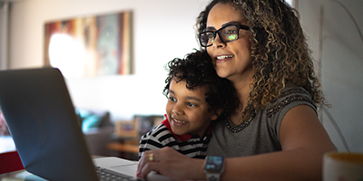 Mom cuddling with her young son while working on computer