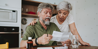 Senior couple in their kitchen taking meds and reviewing Medicare