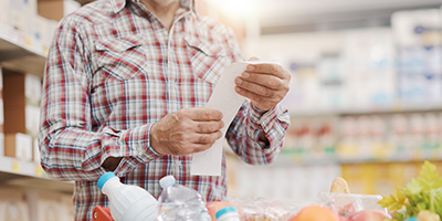 Torso of senior man reviewing his grocery receipt